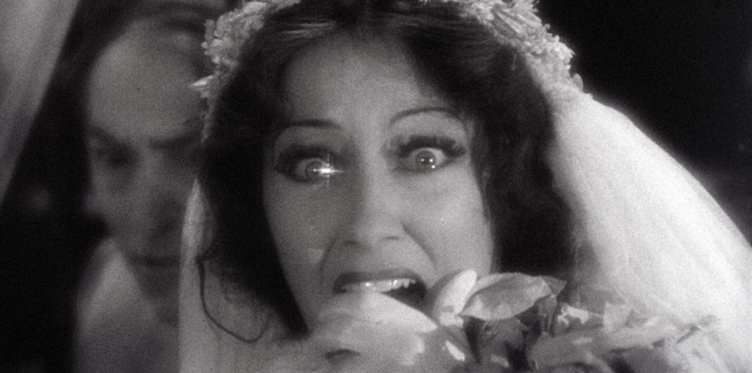 Close-up of Patricia Kelly (Gloria Swanson) in distress, gripping her head, in a dramatic moment from Queen Kelly.